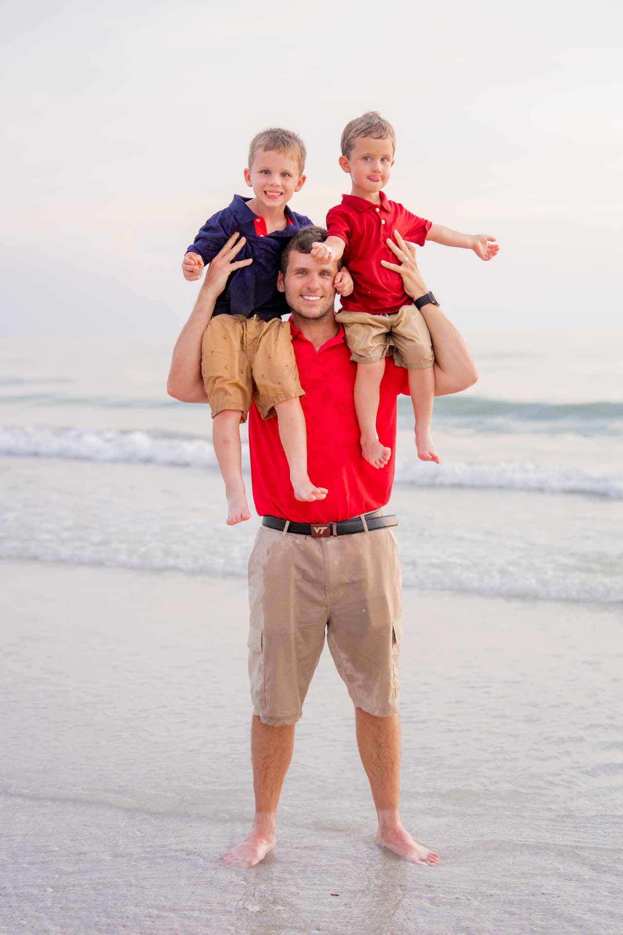 Dad carrying his two young sons on his shoulders at the water's edge