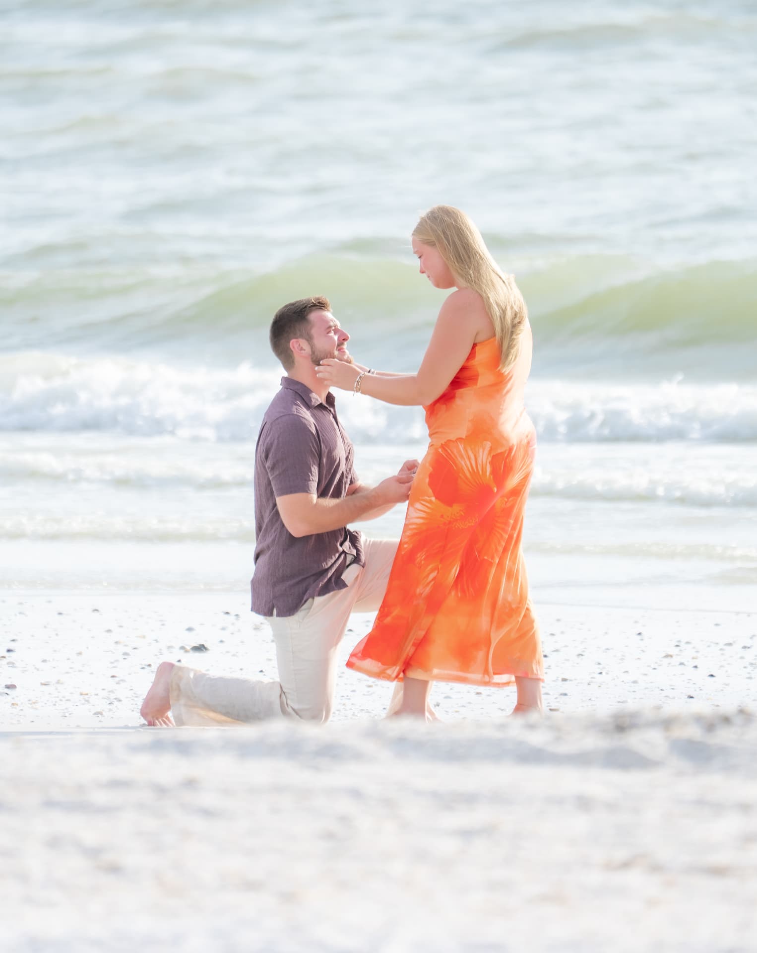 She holds his face at the water's edge moments after he proposed on one knee