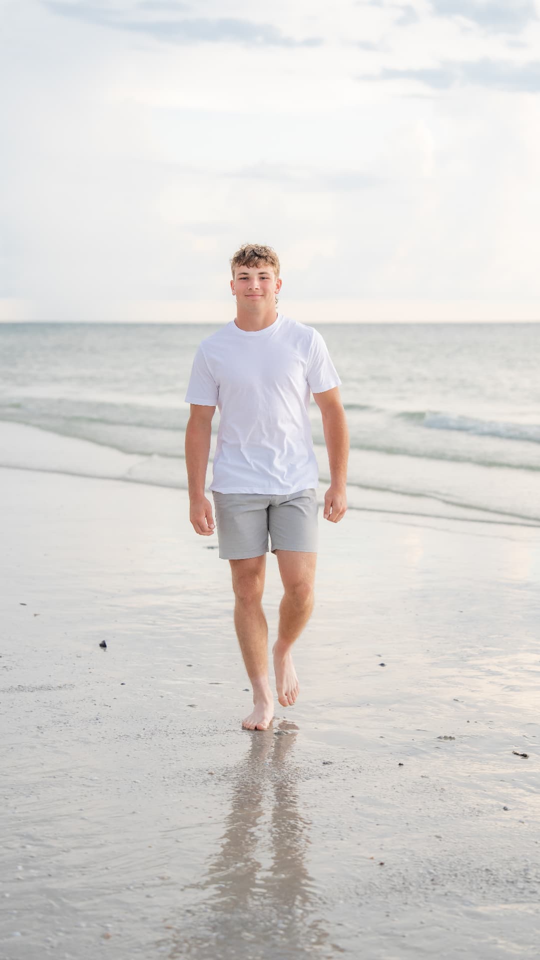 Teen walking along the wet sand at sunset for a senior beach portrait