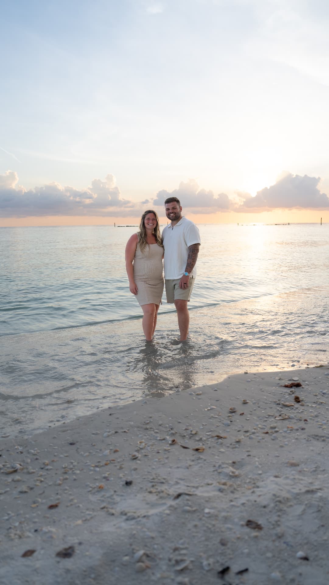 Expectant mother in a flowing dress photographed on a Florida beach at sunset